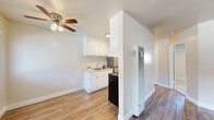 This efficiently designed one-bedroom, one-bathroom unit in Hayward, CA offers a well-organized single-level layout. The living room features wood-look laminate flooring, neutral walls, a ceiling fan with light fixture, and a window overlooking a pool area, providing pleasant natural light and outdoor views. A wall-mounted heater unit serves the living space.

The galley-style kitchen is positioned off the living area, partially separated by a partial wall. It features white upper and lower cabinetry, a tile backsplash, a single-basin sink, an electric range, and a refrigerator. Wood-look flooring continues throughout.

A hallway connects the main living area to the bedroom and bathroom. The bedroom is carpeted and features neutral tones, a mirrored sliding-door closet offering built-in storage, a window with blinds providing natural light, and a flush-mount ceiling fixture. A dedicated closet provides additional storage.

The bathroom includes a full tub-shower combination with a curtain, a toilet, and a window for natural ventilation. Throughout the unit, clean white trim, neutral color palettes, and consistent finishes create a cohesive, move-in-ready aesthetic.