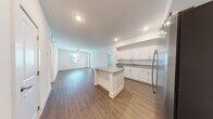 This well-appointed single-floor residence offers a clean, contemporary design highlighted by wood-look flooring and a bright, neutral color palette throughout. The open-concept layout connects the kitchen and living area seamlessly, creating a spacious and functional living environment. The kitchen is a standout feature, showcasing white shaker-style cabinetry, granite countertops, a central island with additional counter space, and a full suite of stainless steel appliances including a refrigerator with ice maker, range, microwave, and dishwasher. Recessed lighting illuminates the kitchen, while a ceiling fan adds comfort to the expansive living area, which also benefits from natural light through a window with blinds. The bedrooms are generously sized, each featuring wood-look flooring, ceiling fans, and windows with outdoor views. The bathrooms are finished with consistent granite vanity tops and white cabinetry. One bathroom includes a sliding glass-door walk-in shower with white tile surround, while another offers a full soaking tub and tiled shower combination with a wide vanity and mirror. The overall ambiance is modern, fresh, and move-in ready, with cohesive finishes and thoughtful details carried throughout the entire space.