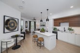 Located at 3585 Aero Dr in San Diego, California, this thoughtfully designed one-bedroom, one-bathroom residence offers a well-appointed single-floor layout with modern finishes throughout. Light wood flooring flows seamlessly across the open-concept kitchen and living area, creating a cohesive and inviting atmosphere bathed in natural light.

The kitchen is a standout feature, showcasing a striking two-tone cabinetry design with warm wood upper cabinets contrasting against sleek white lower cabinets. A white quartz waterfall island with bar seating and bold black pendant lighting serves as the focal point, complemented by stainless steel appliances including a gas range and French door refrigerator, plus a white tile backsplash and matte black fixtures.

The living area offers a comfortable, sunlit space with a ceiling fan and large windows. The bedroom is a serene retreat featuring a ceiling fan, large windows with outdoor views, and ample natural light. Two well-organized closets provide generous storage with built-in shelving and hanging rods.

The bathroom features a warm wood vanity with an illuminated mirror, crisp white walls, and light flooring, connecting conveniently to the bedroom. A private balcony extends the living space outdoors. A clean hallway with louvered closet doors adds to the home's refined, contemporary character.