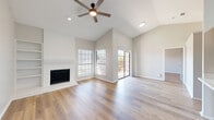Located at 4804 Haverwood Lane in Dallas, TX, this 1-bedroom, 2-bathroom home offers a well-designed single-floor layout with standout architectural details throughout. The living room immediately impresses with soaring vaulted ceilings, a ceiling fan with integrated lighting, and a brick-surround fireplace flanked by built-in shelving — an ideal focal point for the space. Light hardwood-style luxury vinyl plank flooring runs throughout, adding warmth and continuity. Multiple windows and a sliding glass door flood the living area with natural light while providing direct access to the private balcony with outdoor views. The kitchen is efficiently laid out with gray shaker-style cabinetry, white countertops, a double-basin stainless steel sink, and black appliances, including a refrigerator and dishwasher. A skylight above the kitchen passthrough adds an additional source of natural light. The bedroom is a comfortable, well-proportioned retreat with its own ceiling fan and generous closet space. Two full bathrooms include a tiled tub-shower combination. Additional conveniences include a dedicated laundry area, completing this practical and attractive home in the heart of Dallas.