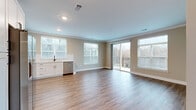 Located at 5672 Peachtree Pkwy in Peachtree Corners, GA, this well-appointed residence offers three bedrooms and four bathrooms across a thoughtfully designed single-level floor plan. The open-concept living and kitchen area is bright and airy, filled with natural light from multiple large windows and a sliding glass door that opens to a private balcony with outdoor views. Rich hardwood-style flooring runs throughout the main living spaces, complemented by crown molding that adds a refined touch.

The kitchen is a standout feature, showcasing crisp white shaker cabinetry, light countertops, a classic tile backsplash, and a full suite of stainless steel appliances including a range, over-the-range microwave, dishwasher, and side-by-side refrigerator. An in-unit stacked washer and dryer is conveniently tucked nearby.

The bedrooms are carpeted for comfort, with the secondary bedrooms featuring natural light from windows overlooking the surroundings. The bathrooms are finished with white cabinetry accented by matte black hardware, soaking tub and shower combinations, and built-in shelving for added storage. Neutral warm-toned walls throughout create a cohesive and welcoming ambiance across the entire home.