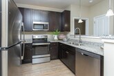 This single-story residence at 700 SR-96 E in Bonaire, Georgia, offers a thoughtfully designed layout with a cohesive, neutral aesthetic throughout. The open-concept kitchen serves as a functional centerpiece, featuring rich dark cabinetry, granite countertops, stainless steel appliances, and a breakfast bar illuminated by pendant lighting. Light wood-style flooring runs through the kitchen and connects seamlessly to the surrounding living areas.

The living room is a comfortable, well-lit space with a ceiling fan, large windows dressed in floor-length drapes, and warm, neutral tones that create a relaxed atmosphere. Multiple bedrooms provide versatile accommodations, each equipped with ceiling fans, natural light from windows with blinds and curtain panels, and wood-style flooring. The bedrooms maintain a calm, restful ambiance with ample closet space.

The bathrooms continue the granite countertop theme, with dark vanity cabinetry complementing the overall design palette. One bathroom features a tub-shower combination, while another offers additional utility space with built-in shelving. The consistent use of neutral tones, quality finishes, and natural light throughout the home creates a polished and inviting environment.
