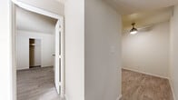 This single-floor unit at 7007 W Indian School in Phoenix, Arizona, offers a clean, neutral aesthetic throughout, with light-toned wood-style flooring running consistently across all rooms. The living area is open and well-proportioned, featuring a textured ceiling, a ceiling-mounted HVAC vent, and a window that brings in natural light and views of the surrounding greenery. The kitchen is thoughtfully laid out with warm wood-tone cabinetry, white countertops, and stainless steel appliances including a refrigerator, dishwasher, and range. An in-unit washer is conveniently located adjacent to the kitchen. The bedrooms are comfortably sized, each equipped with sliding-door closets offering built-in shelving for ample storage. One bedroom features a ceiling fan and a window overlooking the outdoor surroundings. The bathroom includes a wood-tone vanity with storage, a wall-mounted mirror, and a separate shower area. Crisp white walls and clean trim work are present throughout, contributing to a bright and move-in-ready atmosphere. The floor plan flows logically between the living spaces, kitchen, bedrooms, and bath, making the layout practical and easy to navigate.
