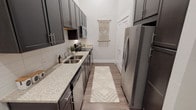 Located at 5402 Middle Fiskville Rd in Austin, TX, this single-story unit offers a thoughtfully designed layout with contemporary finishes throughout. The galley-style kitchen is well-appointed with charcoal gray cabinetry, brushed nickel hardware, granite-look countertops, a double-basin sink, white tile backsplash, and a full suite of stainless steel appliances, including a refrigerator, range, microwave, and dishwasher. Wood-look flooring runs through the kitchen and living areas, adding warmth and continuity.

The living area impresses with soaring ceilings that create an open, airy atmosphere. The space is versatile, accommodating both a lounge area and a dedicated workspace. Natural light filters through windows, connecting the living area to the carpeted bedroom, which benefits from multiple windows that invite ample daylight and outdoor views. The bedroom's tall ceilings mirror the generous scale found throughout the unit.

The bathroom features wood-look flooring, a tiled soaking tub with shower combination, a granite-topped vanity with dark cabinetry, and clean white walls. Overall, the unit presents a cohesive, modern aesthetic with a neutral palette and elevated ceiling heights that enhance the sense of space throughout.