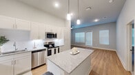 Located at 1619 N Frazier Street in Conroe, Texas, this well-appointed single-story home offers four bedrooms and two bathrooms across a thoughtfully designed floor plan. The open-concept kitchen and living area serves as the heart of the home, showcasing crisp white shaker cabinetry, granite countertops, a central island with pendant lighting, and a full suite of stainless steel appliances. Light wood-look flooring flows through the main living areas, complemented by neutral gray walls and abundant natural light streaming through multiple windows. The living room features a ceiling fan and a door providing outdoor access. The primary bedroom is generously sized, accompanied by a walk-in closet with built-in shelving and a private en-suite bathroom featuring a glass-enclosed tile shower and granite vanity. Additional bedrooms offer a mix of wood-look and carpeted flooring, each with natural light from window blinds. The second bathroom includes a full soaking tub with tile surround. Hallways connect the layout efficiently, and two closets offer ample storage. The home presents a clean, modern aesthetic with consistent finishes that create a cohesive and comfortable living environment throughout.