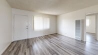 Located at 7746 Bright Ave in Whittier, California, this single-story 2-bedroom, 1-bathroom unit offers a practical and well-organized layout. Wood-look luxury vinyl plank flooring runs consistently throughout the home, lending a clean, cohesive aesthetic to every room. The living room is an open, light-filled space featuring a large window with vertical blinds, a textured ceiling, and a wall-mounted heater unit. It connects seamlessly to the rest of the home via a central hallway. The kitchen is equipped with warm honey-toned wood cabinetry, dark countertops, a stainless steel gas range with over-the-range microwave, and a double sink beneath a window that draws in natural light. A wall-mounted AC unit provides climate control. The adjacent dining area offers additional space for everyday living. Both bedrooms are comfortably sized with textured ceilings and individual closets featuring sliding or hinged panel doors, providing ample storage. The primary bedroom includes two closets. The bathroom features a tub and shower combination with sliding glass doors, pink tile surround, a wood-toned vanity, and a window for natural ventilation. Three total closets throughout the unit add to the home's storage capacity.