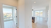 This well-appointed 2-bedroom, 2-bathroom residence offers a thoughtfully designed single-level layout with a clean, modern aesthetic. Light wood-tone flooring runs throughout, complementing the crisp white walls and creating a bright, cohesive feel across the space.

The open-concept kitchen and living area serves as the heart of the home. The kitchen is outfitted with two-tone cabinetry — combining warm wood uppers with sleek dark lower cabinets — paired with white quartz countertops, a geometric tile backsplash, and stainless steel appliances including a French door refrigerator, electric range, and built-in microwave. A large center island with an undermount sink provides additional prep space and casual seating. Oversized windows flood the area with natural light and frame views of the surrounding urban landscape.

Both bedrooms are generously sized, each featuring ceiling fans and large windows that bring in abundant daylight and outdoor views. The primary bedroom benefits from a spacious layout with direct access to a dedicated closet.

The bathrooms reflect the same modern design sensibility, featuring dark navy-blue cabinetry, white countertops, matte black fixtures, and large mirrors with integrated lighting. Frosted glass interior doors add a sophisticated, contemporary touch throughout the unit.