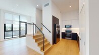 Located in the sought-after Silver Lake neighborhood of Los Angeles, this contemporary unit at 1901 Blake Ave showcases a clean, modern aesthetic throughout. Light-toned hardwood flooring flows seamlessly across the open-plan living areas, complemented by crisp white walls and recessed lighting that enhance the bright, airy atmosphere.

The kitchen is a standout feature, designed with a two-tone cabinet scheme pairing dark lower cabinetry with white upper cabinets that extend to the ceiling, maximizing storage. Stainless steel appliances—including a French door refrigerator, range, microwave, and dishwasher—are integrated throughout, while a sleek white countertop with a matte black faucet adds a refined contrast. Generous counter space and an efficient galley-style layout make the kitchen both functional and visually striking.

A modern staircase with light wood treads and a steel cable railing serves as an architectural focal point, adding an industrial-contemporary touch to the space. The living area benefits from large black-framed windows and glass doors that open to an outdoor area, flooding the interior with natural light and offering open views of the surrounding neighborhood.

The bathroom features bold geometric patterned floor tiles in a three-dimensional diamond motif, paired with white subway tile in the tub surround, a dark vanity with a white basin, and matte black fixtures throughout, creating a visually dynamic yet cohesive design.