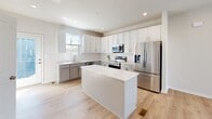 Located at 1601 Overbrook Rd in Richmond, Virginia, this modern multi-floor home spans three levels and showcases a clean, contemporary design with light-toned hardwood flooring, recessed lighting, and a neutral color palette throughout. The main living area is open and airy, with a ceiling fan overhead and a staircase with a wood handrail connecting the floors. Natural light flows freely through multiple windows fitted with blinds, enhancing the bright and welcoming ambiance. The well-appointed kitchen is a standout feature, offering white and gray shaker-style cabinetry, a subway tile backsplash, quartz countertops, stainless steel appliances including a range, microwave, dishwasher, and refrigerator, and a central island that provides additional workspace and storage. The bedrooms are generously sized, each with ceiling fans, ample natural light, and access to walk-in closets. The bathrooms are finished with hexagonal tile flooring, quartz vanity tops, and gray cabinetry with brushed gold hardware. One bathroom features a glass-enclosed walk-in shower, while another includes a tiled tub-shower combination. The upper level offers vaulted ceiling accents and additional living or bedroom space, completing this thoughtfully designed Richmond home.