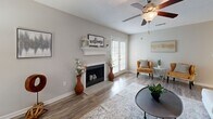 This thoughtfully designed 2-bedroom, 2-bathroom single-floor home offers a comfortable and functional layout across a well-utilized footprint. The living room serves as the heart of the home, featuring a classic fireplace with a white mantel, wood-look flooring, a ceiling fan, and French doors that invite natural light. Adjacent to the living room, the dining area provides an intimate space with neutral tones and warm wood-look flooring, ideal for everyday meals or entertaining. The kitchen is well-equipped with white shaker-style cabinetry, quartz countertops, a subway tile backsplash, stainless steel appliances, and wood-look flooring, offering both style and practicality. The spacious primary bedroom features plush carpeting, a ceiling fan, and a bright window, creating a serene retreat. The second bedroom mirrors this comfort with carpet flooring and a ceiling fan. Both bathrooms are finished with white cabinetry, quartz countertops, wood-look flooring, and shower-tub combinations. A dedicated in-unit laundry area with overhead shelving adds everyday convenience. Throughout, the home maintains a cohesive neutral palette, creating a bright and welcoming ambiance.