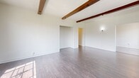 This 900 square foot apartment in Los Angeles offers a harmonious blend of modern convenience and vintage charm. The spacious living area is highlighted by exposed wooden beams, adding character to the crisp white walls and dark hardwood floors. Large windows flood the space with natural light, creating an airy atmosphere.

The kitchen, while compact, is efficiently designed with white cabinetry, a gas range, and a refrigerator. A distinctive turquoise backsplash adds a pop of color to the otherwise neutral palette. The bedroom, measuring 220 square feet, provides ample space and continues the hardwood flooring theme.

One of the bathrooms showcases a retro-inspired design with mint green hexagonal floor tiles and matching wall tiles, creating a visually striking space. Built-in storage solutions, including a vanity in the hallway and closet space, offer practical organization options.

The apartment's layout includes two hallways, enhancing the flow between rooms. A decorative fireplace in the main living area serves as a focal point, adding to the home's charm. The property's single-story layout and thoughtful design make efficient use of its 900 square feet, creating a comfortable and inviting living space in the heart of Los Angeles.