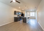 Located at 7117 19th St in Lubbock, Texas, this single-story home offers a well-designed open-concept layout that seamlessly connects the kitchen, dining, and living areas. The kitchen is a standout feature, equipped with dark espresso-toned cabinetry extending to the ceiling, a suite of black appliances including a refrigerator, range, and microwave, and a large central island with a white countertop and pendant lighting overhead. Light wood-look flooring runs throughout the main living areas, contributing to a clean, contemporary aesthetic. The spacious living area benefits from recessed lighting and a ceiling fan, creating a comfortable and well-lit environment. Natural light flows in through blinded windows, adding brightness to each room. The bedrooms feature plush carpeting, ceiling fans, and windows that allow ample natural light. The bathrooms are finished with dark wood vanities, white countertops, tile-surround tub-shower combinations, and wood-look flooring, maintaining a consistent design language throughout the home. The entry area provides a welcoming transition into the open main living space. Overall, the home presents a modern, cohesive interior with practical finishes suited for comfortable everyday living.