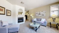 This single-floor residence offers a thoughtfully designed layout that balances comfort and functionality throughout. The living room serves as the heart of the home, anchored by a striking white fireplace with an arched decorative niche above the mantle. Plush carpeting, neutral wall tones, and a seamless sightline into the kitchen create a warm, open atmosphere ideal for both relaxing and entertaining.

The kitchen is outfitted with crisp white cabinetry, granite-style countertops, wood-look flooring, and black appliances including a gas range with over-the-range microwave and a full-size refrigerator — providing ample workspace and storage.

Both bedrooms are generously sized, featuring vaulted ceilings with ceiling fans, soft carpeting, and abundant natural light. The primary bedroom includes a sliding-door closet, offering practical storage solutions. Each bathroom is finished with white cabinetry, granite-style countertops, a single basin sink, and wood-look flooring. One bathroom features a walk-in shower, while the other includes a shower-tub combination.

A dedicated laundry room with a full-size washer and dryer rounds out the practical amenities of this residence, making it a complete and convenient living space.