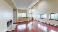 Located at 535 S Burdick St in Kalamazoo, Michigan, this single-floor residence offers a thoughtfully designed layout with a variety of upscale finishes throughout. The spacious living area immediately impresses with soaring vaulted ceilings, gleaming rich hardwood floors, and an abundance of natural light pouring in through multiple large windows fitted with vertical blinds. Elevated transom-style windows line the upper walls, further enhancing the open, airy atmosphere. The kitchen is well-appointed with warm honey-toned cabinetry, dark granite countertops, stainless steel appliances including a refrigerator, range, and dishwasher, and light tile flooring that carries a clean, functional aesthetic. The bedroom features plush wall-to-wall carpeting, a generous closet with double doors, and a sliding glass door that opens directly onto a private balcony, offering expansive views of the surrounding cityscape. The bathroom is finished with matching dark granite countertops, maple cabinetry, a full tub-and-shower combination with white subway tile surround and grab bars, and light tile flooring. Throughout the unit, warm neutral wall tones create a cohesive and inviting ambiance, while baseboard heating and track lighting add to the unit's practicality and comfort.