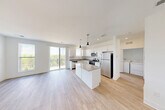 Located at 2501 Avant Ave in Ann Arbor, Michigan, this thoughtfully designed 2-bedroom, 2-bathroom residence offers a clean, modern aesthetic throughout its single-floor layout. The open-concept living and kitchen area serves as the heart of the home, featuring light hardwood-style flooring, crisp white cabinetry, granite countertops, and a central island illuminated by stylish pendant lighting. Stainless steel appliances — including a refrigerator, range, microwave, and dishwasher — complete the well-appointed kitchen. A sliding glass door leads to a private balcony overlooking lush greenery, flooding the living area with natural light. An in-unit washer and dryer provide added convenience. The spacious primary bedroom offers generous square footage with carpet flooring, while the second bedroom also features soft carpet and a large window with outdoor views. Both bathrooms are finished with granite-topped vanities and hardwood-style flooring; the primary bath includes a glass-enclosed shower. Throughout the residence, neutral white walls and consistent finishes create a bright, cohesive atmosphere. A dedicated closet adds practical storage to this well-organized, move-in-ready home.