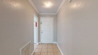 This single-floor home is thoughtfully laid out across a compact yet functional footprint, accommodating three bedrooms, two bathrooms, a kitchen, a hallway, and two closets. The entryway greets residents with light tile flooring, crown molding, and a flush-mount ceiling light, establishing a clean and neutral aesthetic carried throughout the home.

The kitchen features white cabinetry with ample upper and lower storage, light countertops, tile flooring, and white appliances including a range, dishwasher, and refrigerator. A tall, narrow window brings in natural light and offers an outdoor view.

The spacious primary bedroom features carpet flooring, crown molding, a ceiling fan, a large window with outdoor views, and a built-in shelving unit. The two secondary bedrooms also feature carpet flooring, crown molding, ceiling fans, and windows that allow natural light.

Both bathrooms are finished with tile flooring, white vanity cabinetry, and light countertops. One bathroom includes a bathtub, while the other provides a separate toilet and shower area.

Consistent neutral wall tones, white trim, and crown molding throughout the home contribute to a cohesive, clean interior aesthetic.