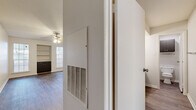 This 1-bedroom, 1-bathroom unit in Austin, TX offers a practical and comfortable single-floor layout. The living room is a bright, open space featuring rich hardwood-style flooring, a ceiling fan with light fixture, built-in shelving for display or storage, and a pass-through window connecting to the kitchen. Natural light flows in through multiple windows with blinds, and a sliding glass door leads to an outdoor area. The kitchen is efficiently designed with dark cabinetry, light speckled countertops, a stainless steel sink, a dishwasher, and a refrigerator, with textured walls adding character. The bedroom offers a comfortable footprint with a ceiling fan, a large window for natural light, and a mirrored sliding-door closet that enhances the sense of space. Two closets provide ample storage throughout the unit. The bathroom features a vanity with dark cabinetry and light countertop, with a separate water closet for added privacy. Hardwood-style flooring flows consistently throughout the unit, complemented by clean white walls and white baseboards, creating a cohesive, neutral aesthetic well-suited for a variety of furnishing styles.