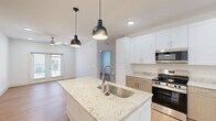 Located at 7135 Mount Zion Circle in Morrow, GA, this well-appointed 2-bedroom, 2-bathroom residence offers a thoughtfully designed single-floor layout with a clean, modern aesthetic throughout. Light wood-style flooring flows seamlessly across the entire space, creating a bright and cohesive atmosphere.

The open-concept kitchen serves as the centerpiece of the home, anchored by a large white island with stunning granite countertops and an undermount stainless steel sink accented by sleek pendant lighting. White upper cabinetry pairs with warm wood-toned lower cabinets, complemented by stainless steel appliances including a range, microwave, and refrigerator. Recessed lighting and additional pendant fixtures ensure excellent illumination throughout.

The kitchen opens directly into the living area, which features a ceiling fan and French doors that invite natural light and provide outdoor access. Both bedrooms are comfortably sized, with the primary bedroom offering a ceiling fan and a window with exterior views. Each bedroom includes a dedicated closet with built-in wire shelving for organization.

The two bathrooms share a consistent design language, each featuring a wood-toned vanity with granite countertops, a framed mirror with bar lighting above, and a full soaking tub with shower combination. The neutral palette and quality finishes throughout give this residence a polished, move-in-ready feel.