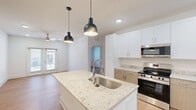 Located at 7135 Mount Zion Circle in Morrow, GA, this well-appointed 2-bedroom, 2-bathroom residence offers a thoughtfully designed single-floor layout with a clean, modern aesthetic throughout. Light wood-style flooring flows seamlessly across the entire space, creating a bright and cohesive atmosphere.

The open-concept kitchen serves as the centerpiece of the home, anchored by a large white island with stunning granite countertops and an undermount stainless steel sink accented by sleek pendant lighting. White upper cabinetry pairs with warm wood-toned lower cabinets, complemented by stainless steel appliances including a range, microwave, and refrigerator. Recessed lighting and additional pendant fixtures ensure excellent illumination throughout.

The kitchen opens directly into the living area, which features a ceiling fan and French doors that invite natural light and provide outdoor access. Both bedrooms are comfortably sized, with the primary bedroom offering a ceiling fan and a window with exterior views. Each bedroom includes a dedicated closet with built-in wire shelving for organization.

The two bathrooms share a consistent design language, each featuring a wood-toned vanity with granite countertops, a framed mirror with bar lighting above, and a full soaking tub with shower combination. The neutral palette and quality finishes throughout give this residence a polished, move-in-ready feel.