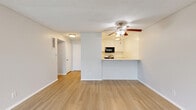 Located at 4200 Harbor Blvd in Oxnard, California, this one-bedroom, one-bathroom residence offers a well-organized single-floor layout designed for comfortable everyday living. The open-concept living and kitchen area serves as the heart of the home, featuring light wood-tone flooring, neutral walls, and a textured ceiling. A ceiling fan with integrated lighting anchors the living space, while a sliding glass door invites natural light and provides access to a private outdoor balcony with low-maintenance landscaping. The kitchen is positioned behind a peninsula-style breakfast bar with seating, offering white cabinetry, a stainless steel range, a built-in microwave, and flush-mount ceiling lighting — a functional and efficient layout. A hallway connects the main living area to the private quarters of the home. The bedroom is generously proportioned with plush carpeting, soft neutral tones, and access to a spacious walk-in closet featuring wrap-around shelving and hanging rods for ample storage. The bathroom is clean and bright, appointed with light wood-tone flooring, a full tub-shower combination with brushed nickel fixtures, and a white vanity. The overall aesthetic is light, airy, and move-in ready, reflecting a simple and practical coastal California sensibility.