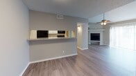 Located at 1920 W Tarrant Rd in Grand Prairie, Texas, this single-story unit offers a well-designed, open layout with a cohesive neutral color palette and durable light-toned wood-look flooring throughout the main living areas. The living room is generously proportioned, featuring a curved accent wall, a ceiling fan with light fixture, and a fireplace that serves as a natural focal point. A pass-through counter connects the living area to the galley-style kitchen, which is outfitted with white cabinetry, light granite-style countertops, black appliances including a refrigerator, range, and dishwasher, and a stainless steel sink — offering both functionality and visual appeal. The bedroom is carpeted for comfort and includes a sliding glass door that opens to a private outdoor space, along with a double-door closet providing ample storage. A second carpeted bedroom with direct kitchen adjacency offers flexibility for various uses. The bathrooms feature granite-style vanity countertops with white cabinetry; one includes a walk-in shower with built-in shelving, while another offers a bathtub. Additional highlights include a walk-in closet, textured ceilings, and consistent modern hardware and fixtures throughout the space.
