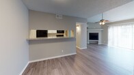 Located at 1920 W Tarrant Rd in Grand Prairie, Texas, this single-story unit offers a well-designed, open layout with a cohesive neutral color palette and durable light-toned wood-look flooring throughout the main living areas. The living room is generously proportioned, featuring a curved accent wall, a ceiling fan with light fixture, and a fireplace that serves as a natural focal point. A pass-through counter connects the living area to the galley-style kitchen, which is outfitted with white cabinetry, light granite-style countertops, black appliances including a refrigerator, range, and dishwasher, and a stainless steel sink — offering both functionality and visual appeal. The bedroom is carpeted for comfort and includes a sliding glass door that opens to a private outdoor space, along with a double-door closet providing ample storage. A second carpeted bedroom with direct kitchen adjacency offers flexibility for various uses. The bathrooms feature granite-style vanity countertops with white cabinetry; one includes a walk-in shower with built-in shelving, while another offers a bathtub. Additional highlights include a walk-in closet, textured ceilings, and consistent modern hardware and fixtures throughout the space.