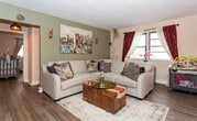Located at 54 High St in Perth Amboy, NJ, this single-floor residence offers a well-organized layout with multiple distinct living spaces. The floor plan, visible in the 3D model, reveals a thoughtfully arranged interior with interconnected rooms designed for everyday functionality.

The living room serves as the heart of the home, featuring hardwood-style flooring, neutral taupe walls, and a large sectional sofa. A bold cityscape painting anchors the space, while a wide window dressed in deep burgundy and sheer curtains allows natural light to fill the room, creating a warm and inviting ambiance.

The kitchen is efficiently designed with white cabinetry, dark countertops, and a classic white subway tile backsplash accented with decorative mosaic tile detailing. A gas range, built-in microwave, and sink are neatly arranged, with a window above providing natural light.

The primary bedroom features hardwood-style flooring, multiple windows with elegant draping curtains, and a warm, neutral color palette. A second bedroom is distinctively finished with deep teal walls adorned with celestial planet decals, creating a dynamic and imaginative atmosphere. Additional rooms visible in the floor plan suggest further versatile living spaces throughout the home.