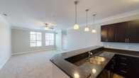 Located at 320 Continental Cir in Christiansburg, Virginia, this single-floor residence offers a thoughtfully designed layout that balances comfort and functionality. The open-concept living and kitchen area serves as the heart of the home, where crown molding and a ceiling fan lend a polished finish to the carpeted living space. Large windows flood the room with natural light and offer views of the surrounding community. The kitchen is outfitted with rich dark cabinetry, dark granite countertops, stainless steel appliances including a refrigerator, range, and microwave, and light hardwood-style flooring. A peninsula with pendant lighting and an integrated double sink connects the kitchen to the living area, making it ideal for entertaining. Two well-sized bedrooms each feature plush carpeting, ceiling fans, and windows that bring in ample natural light. Both bathrooms are finished with dark granite vanity tops, dark wood cabinetry, tile flooring in a warm earth tone, and tub-shower combinations. A dedicated in-unit laundry room with a full-size washer and dryer adds everyday convenience. The overall aesthetic is clean and contemporary, with a neutral color palette throughout that creates a bright, cohesive atmosphere.