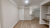 This 1440 square foot apartment in Raleigh, NC offers a blend of modern amenities and natural beauty. The single-floor layout maximizes space efficiency, featuring one bedroom (160 sq ft) and one bathroom. The heart of the home is a contemporary kitchen, boasting stainless steel appliances, granite countertops, and a mix of white and wood-tone cabinetry. The open concept design seamlessly connects the kitchen to the living areas, enhanced by crown molding and recessed lighting.

Neutral tones dominate the interior, with light grey walls and a combination of carpeted and wood-look flooring. The bedroom is spacious and bright, with a ceiling fan and large window. The bathroom features a modern white tub-shower combo with sleek fixtures.

A standout feature is the covered balcony, offering an extension of living space and picturesque views of the surrounding lush forest. This outdoor area, with its white shiplap walls and metal railing, provides a perfect spot for relaxation or entertaining.

The apartment includes two closets for ample storage, and the exterior showcases clean lines with white siding. Located at 10022 Meadow Chase Drive, this property combines the tranquility of a forest setting with the convenience of city living in Raleigh.