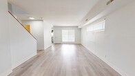 Located at 194 Tompkins Terrace in Beacon, NY, this two-story home offers four bedrooms and two bathrooms spread across two thoughtfully laid-out floors. The main level features an open living room bathed in natural light from large windows fitted with white blinds, complemented by light-toned wood-style flooring that runs throughout the home. The kitchen is well-appointed with dark charcoal shaker-style cabinetry, brushed nickel hardware, white countertops, a stainless steel sink, and white appliances including a range and refrigerator. A staircase with dark treads and a warm wood handrail connects the two floors, adding a refined design detail to the interior. The upper floor hosts the bedrooms, each finished with the same light wood flooring and neutral white walls. Bedrooms include windows that allow natural light, and select rooms feature sliding closet doors for practical storage. The bathrooms are clean and functional, featuring dark wood-tone vanities with white countertops and brushed nickel fixtures. A hallway connects the upper-level rooms efficiently. The home's consistent use of neutral tones, modern finishes, and light-filled rooms creates a bright, clean, and welcoming atmosphere throughout.