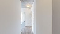 Located in Chicago's vibrant Division Street corridor, this modern 2-bedroom, 3-bathroom residence showcases a sleek industrial-contemporary design. Exposed concrete ceilings contrast beautifully with light hardwood flooring throughout, creating a refined urban aesthetic. Floor-to-ceiling windows flood the living areas with abundant natural light and frame impressive panoramic views of the Chicago skyline and surrounding neighborhoods. A structural concrete column adds an architectural focal point to the open living space. The kitchen is outfitted with high-gloss white cabinetry, gray quartz countertops, a stainless steel gas range, and a striking metallic backsplash that adds depth and character. The hallway features a distinctive exposed concrete ceiling with modern flush lighting, connecting the home's thoughtfully arranged rooms. The bathrooms are finished with large-format tile flooring and dark wood-tone vanities topped with white counters and frameless mirrors. One bathroom includes a soaking tub with dark tile surround. The bedrooms benefit from expansive window walls that offer city and treetop views, filling each room with daylight. A dedicated closet and efficient layout round out this well-appointed urban residence.