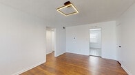Located at 1019 W 41st Pl in Kansas City, MO, this single-floor unit offers three bedrooms, one bathroom, a kitchen, and a connecting hallway within a compact, efficiently organized layout. The floor plan, as illustrated by the 3D model, arranges the rooms in a straightforward configuration connected by a central hallway.

Rich hardwood flooring runs throughout the main living and bedroom areas, providing a warm, consistent aesthetic. Each bedroom features clean white walls, modern square-frame LED ceiling fixtures with gold accents, and windows fitted with horizontal blinds that allow natural light to filter in. The spacious primary bedroom benefits from dual windows, enhancing its bright and airy feel. Secondary bedrooms include closet access and additional doorways connecting to the hallway.

The kitchen is finished with light wood-look tile flooring, gray cabinetry, white subway tile backsplash, and black stainless steel appliances including a gas range, microwave, and refrigerator. A window above the counter adds natural light to the cooking space.

The bathroom features mosaic tile flooring, a wood-toned vanity with integrated sink, a tub-shower combination with white tile surround, and a window for ventilation and natural light. Overall, the unit presents a clean, updated interior with consistent modern finishes throughout.
