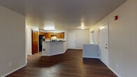Located at 6614 North Cedar Road in Spokane, WA, this single-floor residence offers a well-organized and functional layout designed for comfortable everyday living. The open-concept main living area is finished with rich, dark hardwood-style flooring that extends throughout the entryway, kitchen, and living spaces, creating a cohesive and polished look.

The kitchen is equipped with warm-toned wood cabinetry, ample counter space, a tile backsplash, and black appliances including a refrigerator, range, and dishwasher. A peninsula counter separates the kitchen from the living area, providing additional workspace and a casual dining option.

The living area is bright and open, benefiting from natural light through a large sliding glass door that leads to a private outdoor patio — ideal for enjoying the Spokane surroundings. A side window near the entryway adds additional natural light to the space.

The bedrooms feature plush carpeting, large windows that invite natural light, baseboard heating, and generous closet space, including a walk-in closet in one of the rooms. The bathroom is appointed with a vanity, tub-shower combination, and hardwood-style flooring, and notably includes a dedicated in-unit laundry area — a practical and convenient feature. The overall ambiance is clean, neutral, and move-in ready.