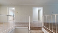 This single-floor home offers a practical and comfortable layout across three bedrooms, two bathrooms, a kitchen, a closet, and two hallways that connect the space efficiently. The interior is finished in a neutral, soft gray palette throughout, creating a clean and cohesive aesthetic.

The bedrooms are carpeted and feature crown molding, baseboard heating, and windows that allow natural light to filter in. The primary bedroom is generously sized and includes access to an adjoining bathroom, offering added convenience. The two additional bedrooms are well-proportioned and share similar finishes, making them versatile for various uses.

The kitchen is equipped with white cabinetry, a stainless steel dishwasher, a countertop sink with brushed nickel fixtures, and a dedicated storage closet with built-in shelving — ideal for a pantry or laundry area, as evidenced by the washer hookup visible on the wall.

Both bathrooms are finished with light wood-look flooring, white vanities, and straightforward, functional fixtures. One bathroom features a vanity with a mirror and overhead lighting, while the second is compact and includes a window for natural ventilation.

The hallways, accented by white railings and light wood-look flooring, provide smooth transitions between rooms. Overall, this home offers a clean, move-in ready environment with practical features throughout.