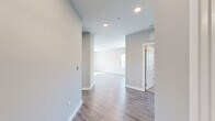 This single-floor residence offers a clean, modern aesthetic defined by neutral gray tones, crisp white trim, and consistent hardwood-style flooring throughout the main living areas. The open-concept layout connects a welcoming hallway to a bright living area, where a large window with vertical blinds frames views of lush greenery, filling the space with natural light.

The kitchen is a functional centerpiece, featuring white shaker-style cabinetry, granite countertops, a classic subway tile backsplash, and a full suite of stainless steel appliances including a refrigerator, range, and microwave. A peninsula with pendant lighting adds both workspace and visual appeal.

The bedrooms are finished with plush carpeting and ceiling fans, creating a comfortable and restful atmosphere. Each room benefits from natural light through windowed walls with vertical blinds.

The bathrooms are thoughtfully designed. One features a full tub-shower combination with large-format white subway tile and brushed nickel fixtures. The other offers a spacious vanity with granite countertops, white cabinetry, and wood-look flooring. Recessed lighting throughout the unit provides consistent, well-distributed illumination, contributing to the overall bright and polished character of this move-in-ready residence.