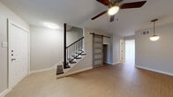 This two-story home in New Braunfels, Texas offers a thoughtfully designed layout with contemporary finishes throughout. The main living area features light luxury vinyl plank flooring, ceiling fans, and a striking staircase with dark wood treads and black metal balusters. A standout rustic sliding barn door with frosted glass panels adds character and serves as a functional design element connecting spaces on the main floor. The kitchen is well-appointed with gray shaker-style cabinetry, stainless steel appliances including a range, refrigerator, and dishwasher, complemented by a decorative patterned tile backsplash and light quartz countertops. A sliding glass door in the kitchen brings in natural light and provides outdoor access. Upstairs, the bedrooms feature plush carpeting, ceiling fans, and windows with blinds that allow for natural light. The bathrooms are finished with clean, modern details including undermount sinks, matte black fixtures, large mirrors, and a tiled tub-and-shower combination featuring a decorative mosaic accent border. Throughout the home, neutral tones and consistent design choices create a cohesive, move-in-ready atmosphere well suited for comfortable living.