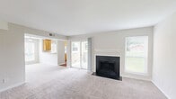 Located at 3340 Hampton Point Dr in Silver Spring, MD, this single-floor residence offers a well-organized layout with one bedroom, two bathrooms, a dedicated closet, and a combined kitchen and living area. The living room serves as the heart of the home, centered around a classic wood-burning fireplace with a white mantel and dark surround. Neutral-toned carpet and multiple windows with blinds fill the space with natural light, creating a bright and welcoming atmosphere. A sliding glass door provides additional access and light to the living area. The kitchen is thoughtfully designed with warm honey-toned wood cabinetry, light stone-finish countertops, and a convenient breakfast bar that opens to the living room. White appliances, including a refrigerator, range, and built-in microwave, complete the functional cooking space. Hardwood-style flooring runs through the kitchen and hallway areas. The bedroom is a comfortable retreat featuring plush carpeting, a ceiling fan with light fixture, and multiple windows that bring in outdoor greenery views. The two bathrooms include warm wood vanities with stone-finish countertops, and one features a full tub-shower combination with tile surround, all set on hardwood-style flooring.