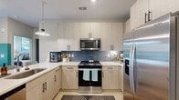 Located on Point Place in Mooresville, NC, this thoughtfully designed single-floor residence offers two bedrooms, two bathrooms, two closets, and a welcoming entrance that flows seamlessly through the home. The interior is defined by light wood-toned flooring, bold dark-painted panel doors with matte black hardware, and a cohesive modern aesthetic throughout.

The kitchen is a functional centerpiece, featuring light wood cabinetry extending to the ceiling, stainless steel appliances including a range and French door refrigerator, a crisp white countertop, and a striking blue subway tile backsplash accented by a pendant light fixture.

The primary bedroom is a vibrant retreat with rich green accent walls, natural light streaming through large windows with outdoor views, a ceiling fan, and ample space for furnishings. The second bedroom echoes a similarly refined design with soft gray tones, large windows overlooking the surrounding landscape, and a cozy window seating nook.

Each bathroom is well-appointed — one features a dual-sink vanity with white countertops and marble-tiled walls, while the other includes a single vanity with a glass-enclosed tub-shower combo and direct access to a dedicated closet. The living area rounds out the space with ceiling fans, bold accent walls, and natural light from oversized windows.