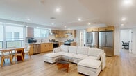 Located at 1165 West 37th Place in Los Angeles, this thoughtfully designed single-floor residence offers six bedrooms and six bathrooms within a clean, modern layout. Light oak hardwood flooring runs throughout, complementing the bright white walls and recessed lighting that give the home a fresh, contemporary feel.

The well-appointed kitchen is a standout feature, boasting light maple shaker cabinets, white quartz countertops, a marble-style tile backsplash, and a full suite of stainless steel appliances including dual gas ranges, a dishwasher, and a French door refrigerator — ideal for high-occupancy living. The adjacent living area provides a comfortable shared gathering space.

Each of the six bedrooms is bright and efficiently laid out, with large windows that invite generous natural light and views of surrounding greenery. Select bedrooms include built-in wardrobe storage with mirrored panels. The six bathrooms are uniformly finished with elegant marble-style walk-in showers featuring mosaic tile bases and matte black or brushed hardware accents.

A dedicated laundry area with dual stacked washer-dryer units adds significant convenience. The overall design emphasizes clean lines, functional spaces, and a neutral palette, making this a well-suited property for shared or multi-occupant living in the heart of Los Angeles.