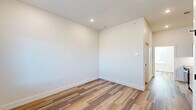 Located at 220 N Walton Blvd in Bentonville, Arkansas, this thoughtfully designed one-bedroom, one-bathroom unit delivers a clean, modern aesthetic across its single-floor layout. Wood-look plank flooring flows seamlessly throughout, complementing the crisp white walls and recessed lighting that create a bright, airy atmosphere.

The galley-style kitchen is a standout feature, outfitted with flat-front cabinetry in a warm natural wood tone, dark quartz countertops, a subway tile backsplash, and a full suite of stainless steel appliances including an electric range, over-the-range microwave, and refrigerator. A sleek single-basin sink with a matte black faucet adds a contemporary finishing touch.

The bedroom is a comfortable and well-proportioned space with clean white walls and the same warm flooring, offering a calm and versatile retreat. A large window allows natural light to fill the room, which also features a built-in wardrobe cabinet and a stacked in-unit washer and dryer — a highly practical inclusion.

The bathroom continues the modern design language with a tiled tub-shower combination, matte black fixtures and hardware, and a vanity with matching wood cabinetry and dark countertop. The overall design of the unit is cohesive, minimal, and move-in ready, making it an efficient and stylish option in the heart of Bentonville.