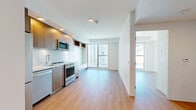 Located on the 20th floor at 370 Queens Quay West in Toronto's vibrant waterfront district, this one-bedroom, one-bathroom unit offers a well-designed layout across a single floor. Light-toned hardwood flooring runs throughout the living areas, creating a warm and cohesive feel.

The kitchen is a standout feature, outfitted with warm wood-grain cabinetry, a marble-style backsplash, and a full suite of stainless steel appliances including a gas range, dishwasher, built-in microwave, and refrigerator. Recessed lighting and a built-in bench with storage add both functionality and style.

The living area is bathed in natural light through floor-to-ceiling sliding glass windows that frame impressive city views, including a direct sightline to the Rogers Centre and the Toronto skyline — a defining feature of this high-floor unit.

The bedroom is a quiet, private retreat with a sliding double-door closet and clean white walls, connected to the rest of the unit via a hallway that also provides access to a walk-in storage area.

The bathroom is finished with large-format tile flooring, a sleek floating white vanity with an undermount sink and illuminated mirror, offering a clean and modern aesthetic throughout.