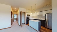 Located at 1688 Stella Avenue in Wenatchee, Washington, this single-floor residence offers a well-designed layout with modern finishes and functional living spaces throughout. The open-concept kitchen is a standout feature, showcasing two-tone cabinetry with crisp white upper cabinets and dark lower cabinets, light quartz countertops, a central island, and a full suite of stainless steel appliances including a range, microwave, dishwasher, and refrigerator. Warm hardwood-style flooring anchors the kitchen, while pendant and track lighting create an inviting atmosphere. The kitchen flows seamlessly into a generous living area finished with plush neutral carpeting and multiple windows that allow natural light to fill the space. The bedrooms are comfortably sized, each with soft carpet flooring, natural light from windows, and sliding-door closets with built-in shelving. Two full bathrooms feature wood-look vinyl flooring, white vanities with dual sinks, and clean white fixtures — one with a tub/shower combo and one with a walk-in shower. A dedicated laundry room with a full-size washer and dryer adds everyday convenience. Additional storage is available via a built-in pantry with open shelving.