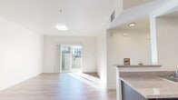 This well-designed single-floor residence offers a clean, contemporary aesthetic throughout, highlighted by crisp white walls, light-toned hardwood-style flooring, and an abundance of natural light. The open-plan living and dining area is airy and welcoming, anchored by sliding glass doors that lead to a private balcony, allowing sunlight to fill the space while providing views of the surrounding neighborhood.

The kitchen is thoughtfully appointed with dark charcoal cabinetry, granite-style countertops, a peninsula with a built-in sink, and a full suite of black appliances including a range and dishwasher. This layout allows for a natural flow between cooking and living spaces.

The bedrooms feature plush carpet flooring and generous proportions, with one room offering direct access to a spacious walk-in closet equipped with wire shelving and hanging rods for ample storage. Additional carpeted rooms provide flexibility for various living arrangements.

The bathroom is finished with matching dark cabinetry, granite countertops, a large mirror, and a full tub-shower combination, all set on easy-to-maintain hardwood-style flooring. Throughout the unit, recessed and flush-mount lighting, along with ceiling vents, ensure comfort and functionality in every room.