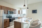 Located at 108 S Bristol St in Sun Prairie, WI, this thoughtfully designed one-bedroom, one-bathroom unit offers a clean, modern aesthetic throughout its single-floor layout. Light hardwood flooring flows continuously across every room, tying the space together with a warm, cohesive feel.

The welcoming entrance leads into an open-concept living area bathed in natural light. The living room features a wall-mounted mini-split system for year-round comfort, complemented by stylish flush-mount lighting and a neutral color palette that enhances the sense of openness.

The kitchen is a standout feature, equipped with warm wood cabinetry, white quartz countertops, a subway tile backsplash, and stainless steel appliances including a range, microwave, and dishwasher. A central island with seating for two, illuminated by sleek pendant lights, serves as both a prep space and casual dining area. Large windows offer pleasant outdoor views.

The dedicated dining area accommodates a full-sized table and benefits from expansive windows that flood the space with natural light and provide views of the surroundings.

The bedroom is quiet and comfortably scaled, while the bathroom features a warm wood vanity with dark countertop, a backlit mirror, and a glass-door walk-in shower with matte black hardware — a polished, spa-like finish.