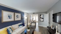 The Darlington is a two-floor, 2-bedroom, 1.5-bathroom residence thoughtfully designed for comfortable, contemporary living. The living room makes a bold first impression with a deep navy accent wall, wood-style flooring, and large windows that bring in natural light. The space flows seamlessly into a dedicated dining area, where French-style doors brighten the room and provide a welcoming atmosphere for entertaining. The kitchen is well-equipped with white shaker cabinetry, granite countertops, a subway tile backsplash, stainless steel appliances, and a breakfast bar — all complemented by a window overlooking the outdoors. Both bedrooms are generously sized with plush carpeting, large windows, and accent walls that add character. The primary bedroom features a walk-in closet, while the second bedroom offers ample storage as well. The full bathroom is finished with granite countertops, a large framed mirror, and a tub-shower combination with elegant marble-style tile surround. A convenient half bathroom adds everyday practicality. Throughout the home, a cohesive navy, gold, and neutral color palette creates a polished and inviting ambiance across both levels.