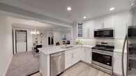 This thoughtfully updated single-floor unit at Jericho Townhomes in Westbury, NY offers a clean, modern aesthetic throughout. The heart of the home is a fully renovated kitchen featuring crisp white shaker cabinetry, marble-look quartz countertops, a subway tile backsplash, and stainless steel appliances including a gas range, microwave, and dishwasher. Light wood-style flooring anchors the kitchen, which flows seamlessly into the dining area and a comfortable living room finished with plush carpet, recessed lighting, crown molding, and a ceiling fan. The living room offers a relaxed ambiance, accented by neutral tones and tasteful décor. The bedroom is generously proportioned, featuring soft carpeting, crown molding, recessed lighting, a ceiling fan, and a window with garden views. An additional carpeted room provides flexible space suitable for a second bedroom or office. The bathroom is elegantly appointed with marble-look tile surrounding a full soaking tub with a glass sliding enclosure, and a sleek vanity. A stacked in-unit washer and dryer adds everyday convenience. Throughout the home, crown molding, recessed lighting, and a cohesive neutral palette create a polished and welcoming atmosphere.