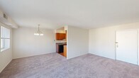 This single-floor residence offers a thoughtfully arranged layout with two bedrooms, two bathrooms, two closets, a kitchen, and a connecting hallway. The open living and dining area is a central highlight, featuring soft carpeting, neutral walls, and abundant natural light streaming in through a sliding glass door that opens to a balcony with outdoor views, alongside an additional window. A chandelier-style light fixture adds a touch of elegance to the dining area. The kitchen is efficiently designed with warm wood cabinetry, dark countertops, hardwood-style flooring, a stainless steel sink, and black appliances including a refrigerator and dishwasher. The spacious primary bedroom is carpeted and filled with natural light from a large window, offering generous proportions and a closet for storage. The second bedroom is equally well-sized, also carpeted, with a window and a wide double-door closet. Both bathrooms share a consistent design featuring white square tile wainscoting, marble-style tile flooring, a tub and shower combination, and a vanity with a white sink. The overall ambiance is clean, bright, and move-in ready.