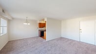 This single-floor residence offers a thoughtfully arranged layout with two bedrooms, two bathrooms, two closets, a kitchen, and a connecting hallway. The open living and dining area is a central highlight, featuring soft carpeting, neutral walls, and abundant natural light streaming in through a sliding glass door that opens to a balcony with outdoor views, alongside an additional window. A chandelier-style light fixture adds a touch of elegance to the dining area. The kitchen is efficiently designed with warm wood cabinetry, dark countertops, hardwood-style flooring, a stainless steel sink, and black appliances including a refrigerator and dishwasher. The spacious primary bedroom is carpeted and filled with natural light from a large window, offering generous proportions and a closet for storage. The second bedroom is equally well-sized, also carpeted, with a window and a wide double-door closet. Both bathrooms share a consistent design featuring white square tile wainscoting, marble-style tile flooring, a tub and shower combination, and a vanity with a white sink. The overall ambiance is clean, bright, and move-in ready.