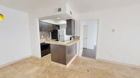 This efficient one-bedroom, one-bathroom unit is thoughtfully laid out across a single floor, making excellent use of every square foot. The combined living, dining, and kitchen area forms the heart of the space, anchored by warm-toned travertine tile flooring that reflects natural light streaming in through a large sliding glass door fitted with vertical blinds. A ceiling fan overhead adds comfort and airflow to the bright, airy living area, which also features a glass-paneled entry door that enhances the sense of openness.

The kitchen is defined by dark espresso cabinetry, a mosaic tile backsplash, light granite countertops, and a functional peninsula that provides both prep space and a casual dining option. Stainless steel and black appliances complete the modern setup, while a pendant light adds a stylish accent above the dining area.

The bedroom is a comfortable, well-proportioned retreat featuring rich hardwood flooring, a ceiling fan, and a window with blinds that invites natural light. It connects conveniently to a dedicated closet and a full bathroom, which is finished with navy blue cabinetry and well-lit vanity fixtures. The clean white walls throughout the unit create a bright, neutral canvas ready for personalization.