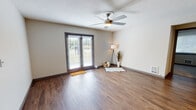 This single-floor unit offers a well-organized layout with distinct living, sleeping, kitchen, and bathroom areas. The living room is a bright, open space anchored by durable wood-style flooring and a ceiling fan overhead. A textured ceiling adds character, while a sliding glass patio door floods the room with natural light and provides outdoor access. Neutral-toned walls throughout create a clean, versatile backdrop.

The kitchen is thoughtfully designed with grey shaker-style cabinetry, light quartz countertops, and a subway tile backsplash in a complementary cool grey tone. Stainless steel appliances, including a refrigerator, electric range, and dishwasher, are integrated seamlessly. A peninsula counter and pendant lighting add both function and visual appeal, while wood-style flooring continues from the living area.

The bedroom offers a quieter atmosphere with plush carpeting, neutral walls, and ample space for furnishings. The bathroom features wood-style flooring, a single-sink vanity with a white countertop and grey cabinetry, and a shower-tub combination, maintaining the unit's consistent, modern aesthetic throughout.